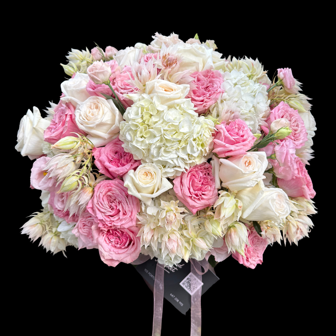 The most luxurious seasonal blooms - Pink and white garden roses, lisianthus, hydrangeas and blushing bride protea in a vase.