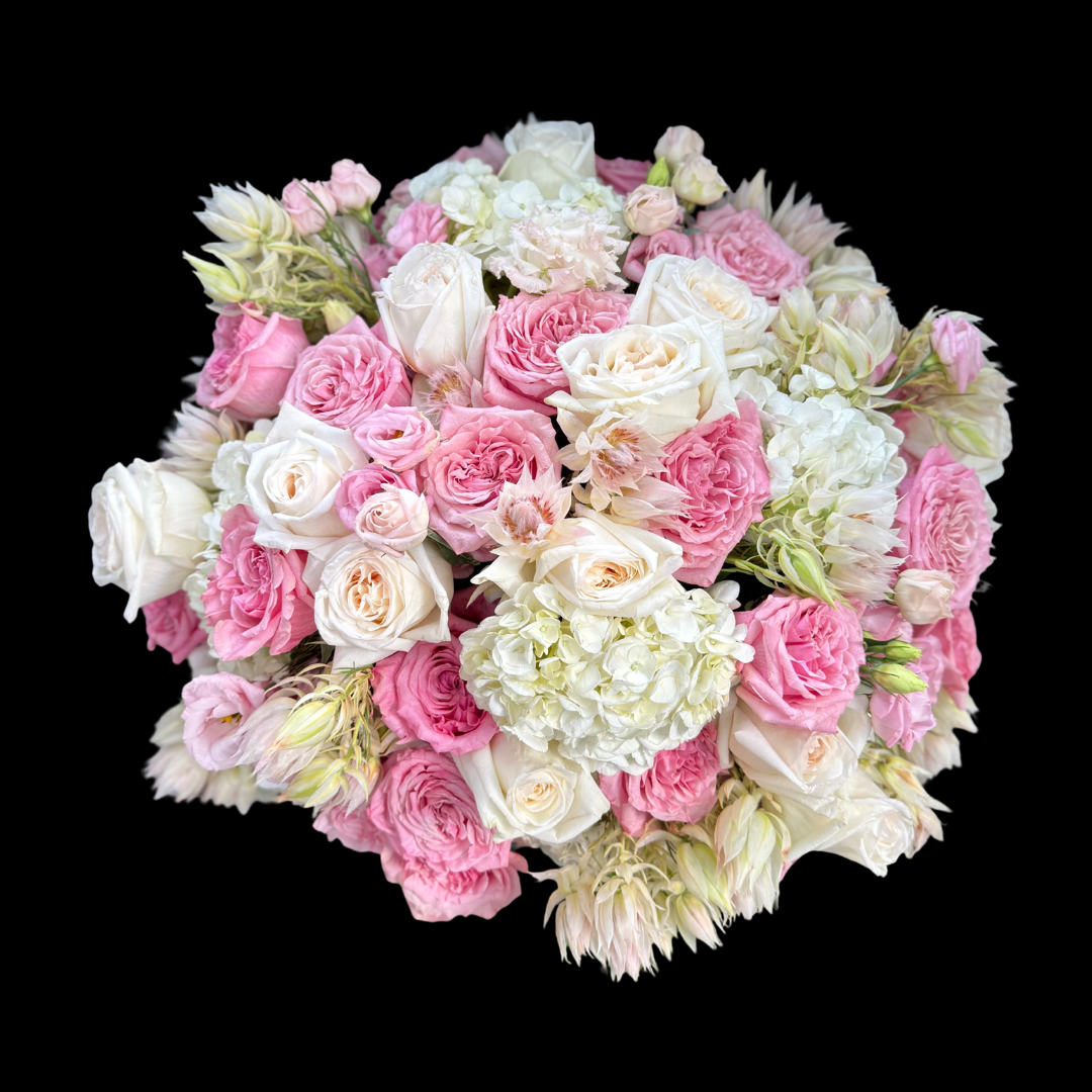The most luxurious seasonal blooms - Pink and white garden roses, lisianthus, hydrangeas and blushing bride protea in a vase.